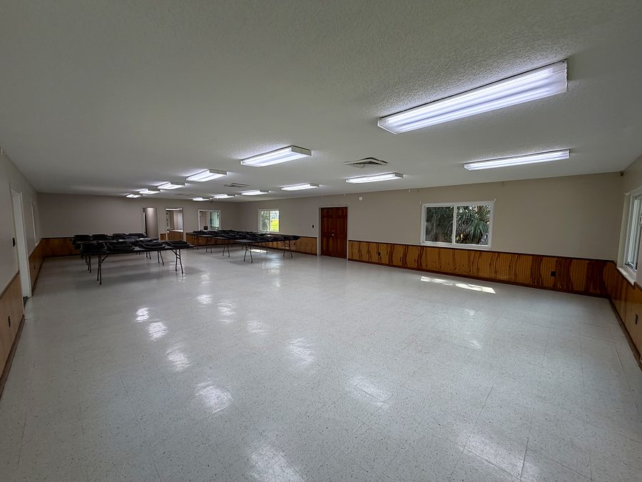 The main hall at the Chem Cell Club, empty, with folding banquet tables and stacked chairs along the wall