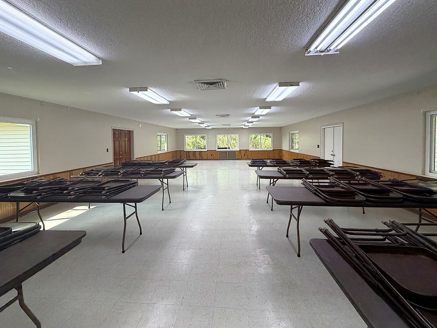The main hall looking the length of the room, folding tables and stacked chairs along both walls